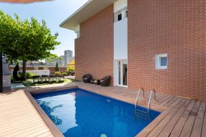 a swimming pool in front of a brick building at Villa Beach Barcelona in Montgat
