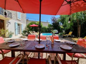 a wooden table with red umbrellas on a patio at La maison des Vendangeurs 6 in Olonzac +6 photos
