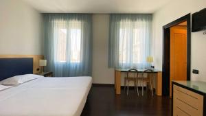 a bedroom with a bed and a desk and two windows at Luxury Rooms Padova Station in Padova
