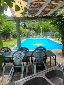 a table and chairs in front of a swimming pool at Finca rural Labriega del hueznar in Cazalla de la Sierra