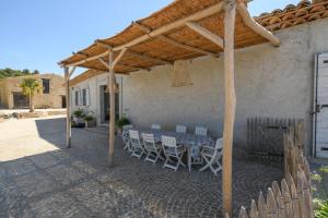 un patio con mesa y sillas bajo una pérgola en La colle aux sources, en Esparron-de-Verdon
