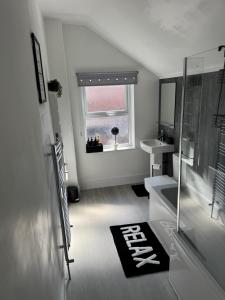a white bathroom with a sink and a window at Elegant 3-Bedroom Home For groups & Families, Patio, Fast Wi-Fi & Parking in Loughborough