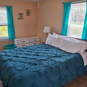 a bedroom with a blue bed with blue curtains at Little Oyster Oasis in White Stone