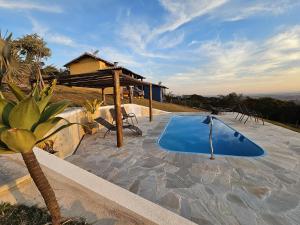 a swimming pool on a patio with a house at Chalés Vila Real - Tranquilidade na Serra de Carrancas - Piscina com uma vista espetacular do Pôr do Sol in Carrancas