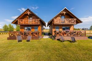 a log cabin with chairs in the grass at Domki w Blasku Słońca in Polańczyk