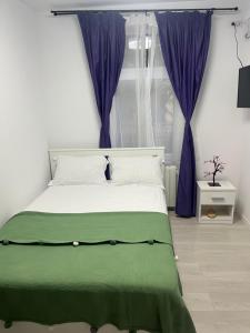 a bedroom with a large bed with purple curtains at Garsoniera lângă Palatul Parlamentului in Bucharest