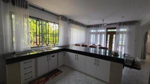 a kitchen with white cabinets and a sink and windows at SaltSunRetreat Villa in Ukunda