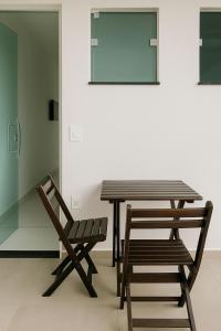 a wooden table and a chair next to a wall at Pousada encanto do sol in Búzios