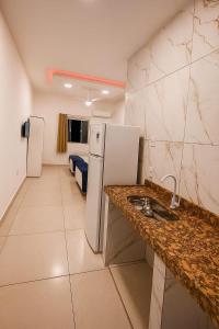 a kitchen with a sink and a refrigerator in a room at Pousada encanto do sol in Búzios