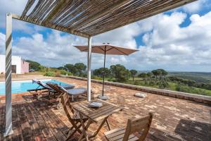 een terras met een tafel, stoelen en een parasol bij Casa da Lua in Aljezur