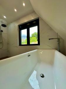 a bathroom with a bath tub with a window at Monte zone in Žabljak