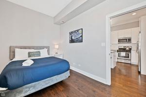 a bedroom with a blue bed and a kitchen at Modern, Spacious 3br Apt Minutes To Downtown! in Chicago