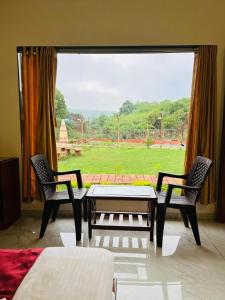 una stanza con un tavolo, due sedie e una finestra di Green Heaven River Side Resort and Villa a Mahabaleshwar Altre 29 foto