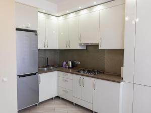 Una cocina blanca con gabinetes blancos y electrodomésticos de acero inoxidable. en Sky House VENETIA Exclusive Apartments, en Chişinău