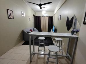a kitchen with a table and stools in a room at Firza Suite in Tanjung Malim