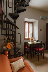 a living room with a table and chairs and a spiral staircase at Grotte Relax in Grotte Santo Stefano