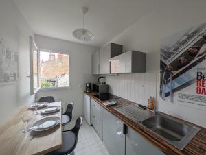 eine Küche mit Spüle und Theke mit Stühlen in der Unterkunft Joli appartement cœur de ville in Poitiers