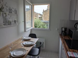 eine Küche mit einem Holztisch mit Stühlen und einem Fenster in der Unterkunft Joli appartement cœur de ville in Poitiers