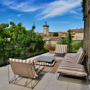 two chairs and a table on a balcony with a clock tower at Le Clos Saint-Sif, 4 BR, air conditioning, pool in Saint-Siffret