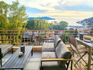 Un patio con un sofá y una mesa en un balcón. en Beau 2 pieces avec vue imprenable sur la rade, en Villefranche-sur-Mer