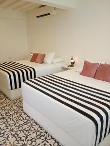 two beds in a white room with black and white stripes at Casa Verde Hotel in Santa Marta