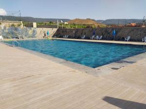 a large swimming pool with blue water and chairs at AUBERGE JOMANA PARK in Azrou