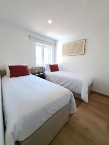 two beds in a room with white walls at Apartamento Vista Mar -Marzaré in Nazaré