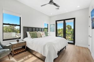 a bedroom with a bed and a chair and windows at Wave Haven Villas - 2 Luxury Villas - 3BR 3 and a Half BA Each - Sleeps 8 Per Unit - Hot Tub - Across from Beach - Rocket and Beach Views in Cocoa Beach