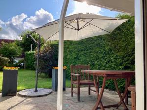 a table with an umbrella and a wooden table and chairs at 4 pers - Modern holiday home with garden, close the Lauwersmeer in Anjum