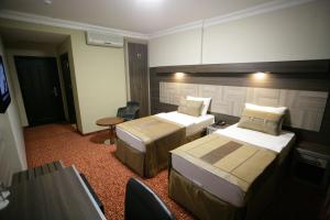 シャンルウルファにあるHotel Guvenのベッド2台とテレビが備わるホテルルームです。
