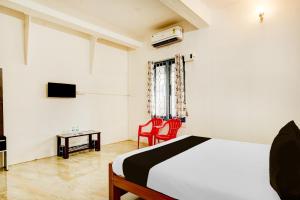 a bedroom with a bed and two red chairs at Hotel O Sky Blue Residency in Chennai