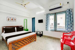 a bedroom with a bed and a red chair at Hotel O Sky Blue Residency in Chennai