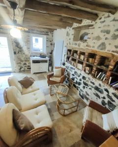 una sala de estar con muebles blancos y una pared de piedra. en La Source de nos Racines, Gîte de caractère, en Beaufort
