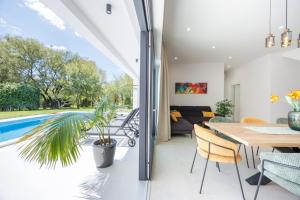 a dining room and living room with a view of a pool at Villa Basini 5km from the centre of Split,Heated pool in Solin