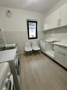a kitchen with two white chairs and a window at Apartament Poiana Câmpina in Poiana Campina