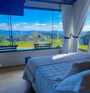 a bedroom with a bed and a large window at Chalé Heinz in Rancho Queimado