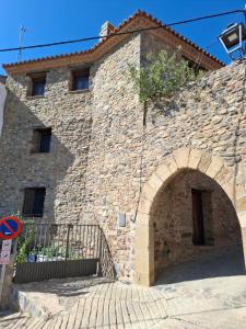 a large stone building with an arch in front of it at La Casa del Arco in Añón