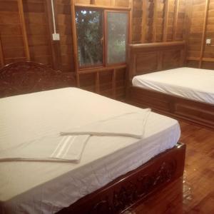 two twin beds in a room with two windows at Luna bungalow chi phat in Chi Phat