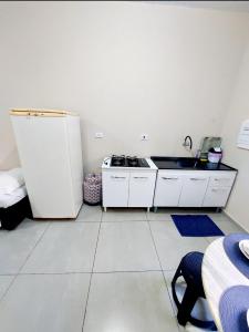 a white kitchen with a sink and a refrigerator at Quarto Privativo Cataratas in Foz do Iguaçu