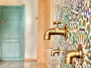 twee bronzen kranen in een badkamer met een mozaïekmuur bij Chanel in Marrakesh +32 foto's