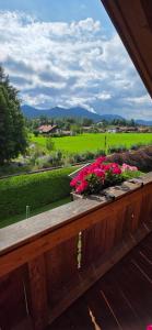a balcony with flowers and a view of a field at Isartraum Brauneck in Gaißach