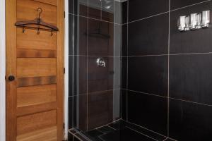 une douche avec des murs carrelés noirs et une porte en bois dans l'établissement Downtown Heritage House and Free Parking, à Joliette 5 autres photos