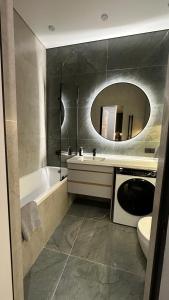 a bathroom with a tub and a sink and a mirror at NEXPO Apartment Бизнес-класс in Astana