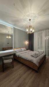 a bedroom with a large bed and a chandelier at NEXPO Apartment Бизнес-класс in Astana