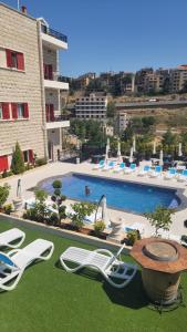 una piscina con sedie e tavolo e un edificio di Terminal K Bhamdoun Hotel a Aley