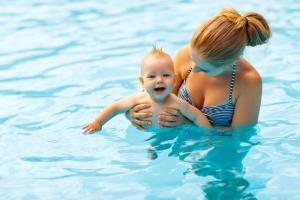 a woman and a baby in a swimming pool at Beautiful Lodge At Manor Park Nearby Hunstanton Beach Ref 23021C in Hunstanton