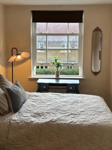 a bedroom with a bed and a window with a table at Cosy central hideout in Ware +10 photos