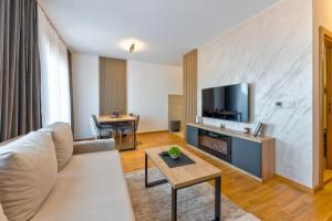 a living room with a white couch and a tv at Boréa Apartments in Zlatibor