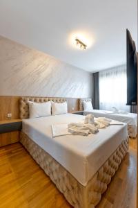a bedroom with a large bed with white sheets at Boréa Apartments in Zlatibor