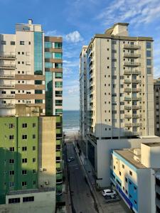Tres edificios altos con el océano al fondo en Lindo Apartamento compartilhado vista MAR, en Itapema